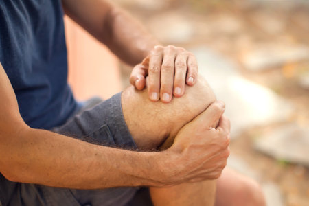 Man with knee pain sitting on the bench in the park. Healthcare and medicine conceptの写真素材