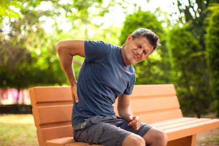 Man with back pain in the park. Healthcare and medicine conceptの写真素材