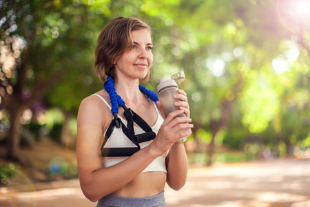Sports woman drinking water in the park. Fitness and healthcare conceptの写真素材