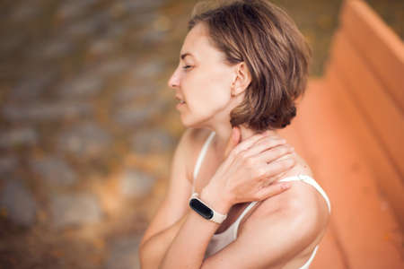 Woman with neck pain in the park. Healthcare and medicine conceptの写真素材