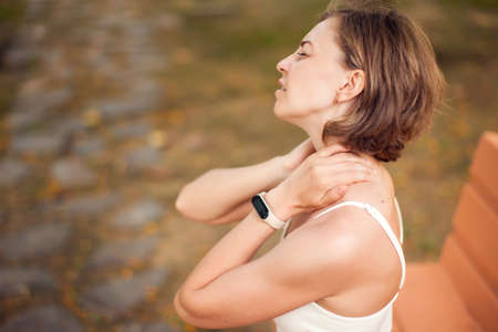 Woman with neck pain in the park. Healthcare and medicine conceptの写真素材
