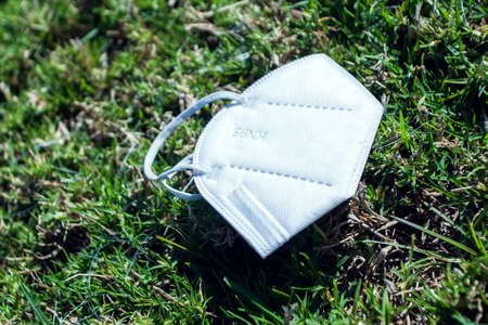 Used face medical mask from  virus thrown away on field grass. World pandemic and environmental...