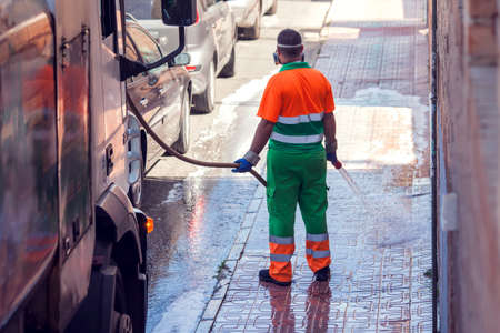 Street cleaning service worker in uniform washing asphalt with special equipmentの写真素材