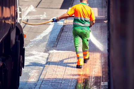 Street cleaning service worker in uniform washing asphalt with special equipmentの写真素材