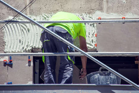 Builder laying tiles on the building. Construction and decorating worksの写真素材