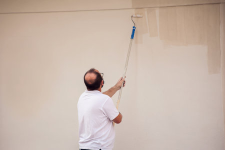 Man painting the wall outdoor with roller. House renovation workの写真素材