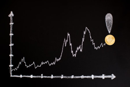 Gold coin on a chalkboard with a graph of the stock marketの写真素材