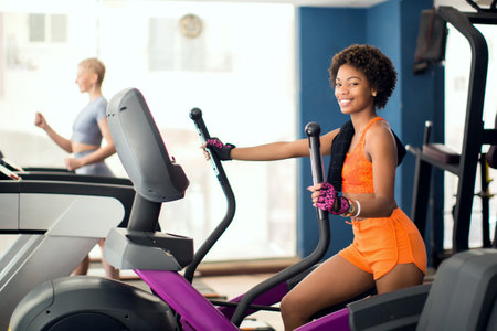fitness, sport, training, gym and lifestyle concept - smiling african american woman exercising on exercise bike in gymの写真素材