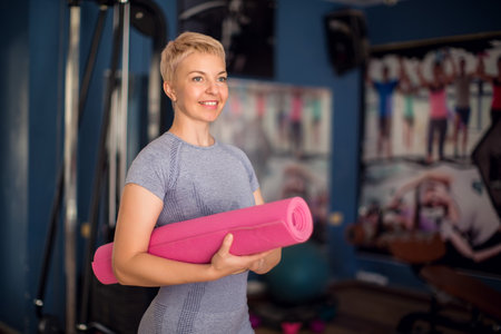 Fitness woman carrying a yoga mat in a gym. Health and lifestyle conceptの写真素材