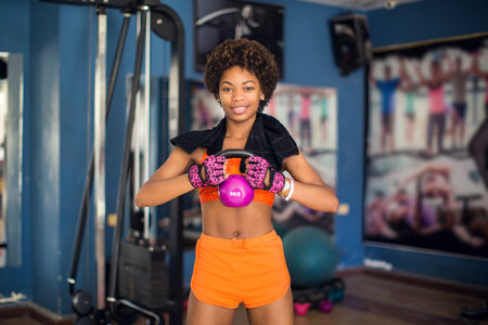 Young african american woman lifting kettlebells in a gymの写真素材