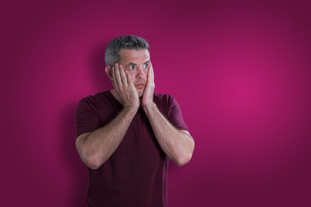 Scared and afraid man on bordo background. Fear emotion conceptの写真素材