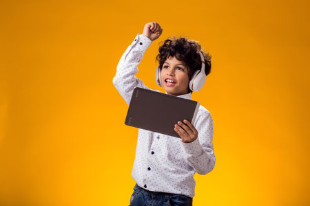 Portrait of child boy using digital tablet and headphones and playing video game. Leisure concept.