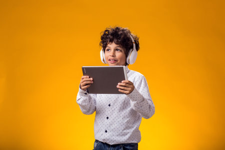 Portrait of child boy using digital tablet and headphones and playing video game. Leisure concept.の写真素材