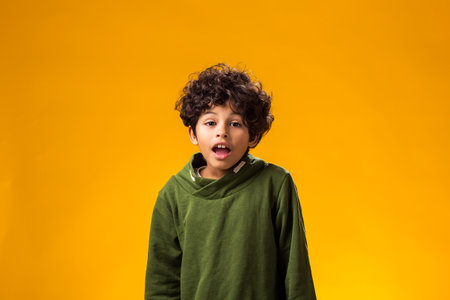Portrait of surprised child boy on yellow background. Children's emotions conceptの写真素材