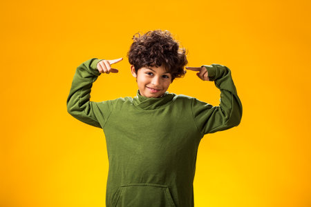 Portrait of smiling child boy pointing at camera on yellow background.の写真素材