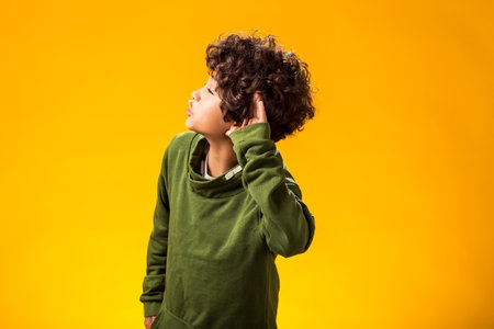 Portrait of eavesdropping child boy keeping hand t his ear. Privacy and curiosity concept.の写真素材