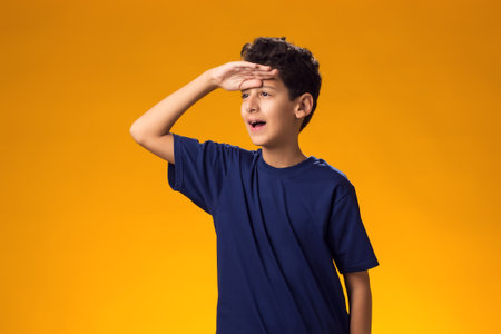 Portrait of child boy holding hand over eyes and looking attentively far away. Curiosity and waiting conceptの写真素材