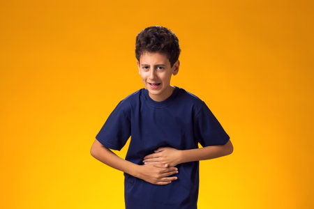 Stomachache. Kid boy suffering from abdominal pain touching aching stomach, holding hands on belly.の写真素材
