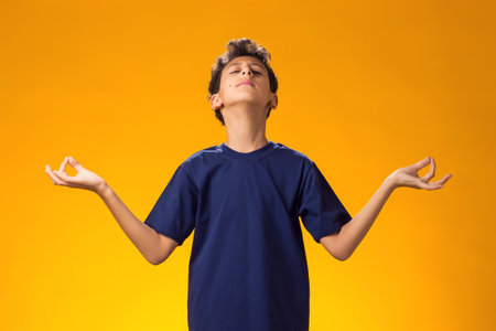 Kid boy smiling peacefully holding his fingers in mudra gesture, meditating. Zen, meditation, consciousness, balance and peace concept.の写真素材
