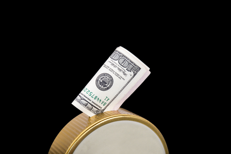 dollar banknote in the hole of saving box isolated on blackの写真素材
