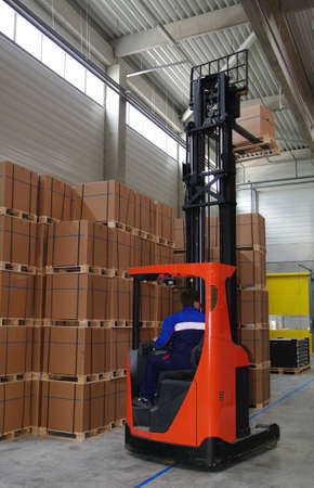 Warehouse worker driving forklift with palette.