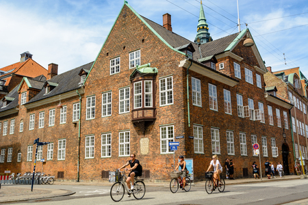 COPENHAGEN, DENMARK - June 24, 2016: Cyclists pedal on a street in Copenhagen. The building behind them represents typical Scandinavian architectureのeditorial素材