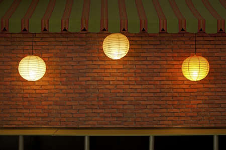 Brick wall with three illuminated lampsの写真素材