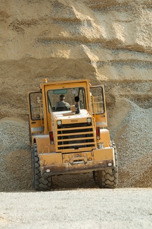 Bulldozer in quarry. Huge pile of limestone and sandの写真素材