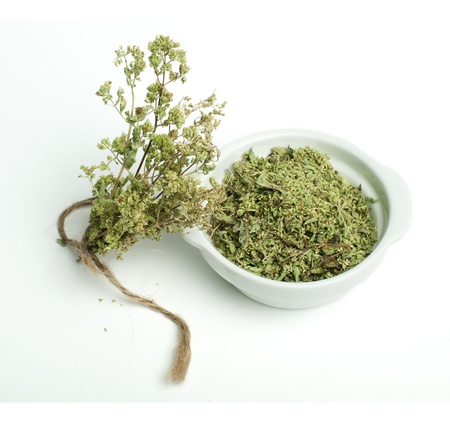 Dried oregano in a bowl and oragano twigs on white backgroundの写真素材