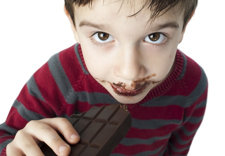 Smiling kid eating chocolate. Smeared stained with chocolate lips. White isolatedの写真素材
