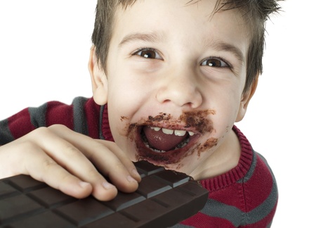 Smiling kid eating chocolate. Smeared stained with chocolate lips. White isolatedの写真素材