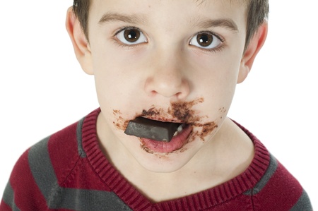 Smiling kid eating chocolate. Smeared stained with chocolate lips. White isolatedの写真素材