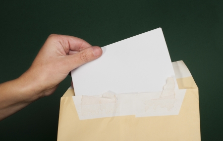 Hand that open a letter from brown envelope. Dark green backgroundの写真素材