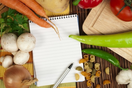 Notebook to write recipes and vegetables around itの写真素材