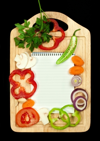 Notebook to write recipes and vegetables around itの写真素材