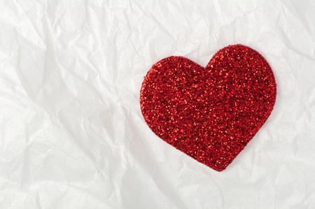Shiny red heart on white crumpled paperの写真素材