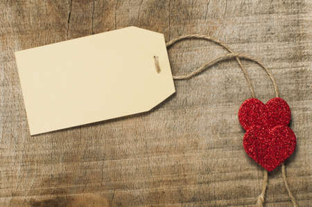 Paper label with rope and red hearts on wooden backgroundの写真素材