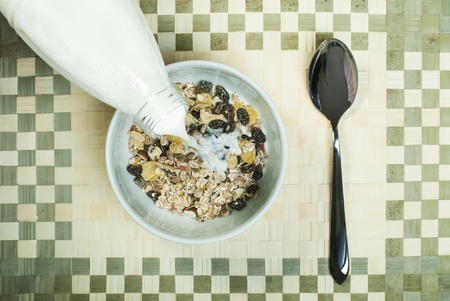 Muesli breakfast in package.Bottle milk and spoon. Pouring milk in a bowlの写真素材