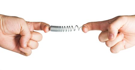 Two hands stretching spring.Stretched spring. Resistance and opposition metaphor.の写真素材