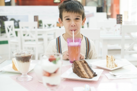Child drink lemonade. Cake and a milkshake in confectionery.の写真素材