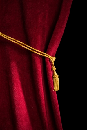 Red velvet curtain with tassel. Close up black isolated curtainの写真素材