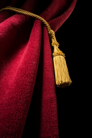 Red velvet curtain with tassel. Close up black isolated curtainの写真素材