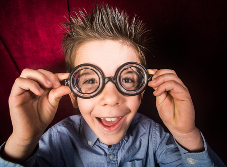 Smiled child with big glasses. Red curtain 