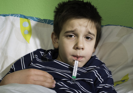 Sick child in bed. Measuring the temperature with a thermometer.
