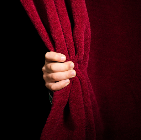 Hand appearing beneath the curtain. Red curtain.の写真素材