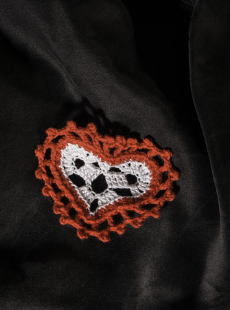 Heart shape made of red textile on black satin