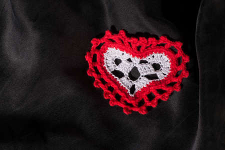 Heart shape made of red textile on black satin