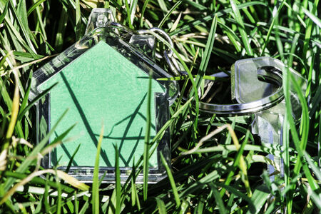 Shape of a house on grass and keys. Sun lightの写真素材