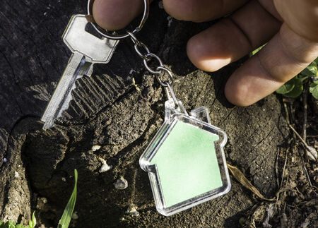 Keychain in a shape of house on wood. Green color houseの写真素材