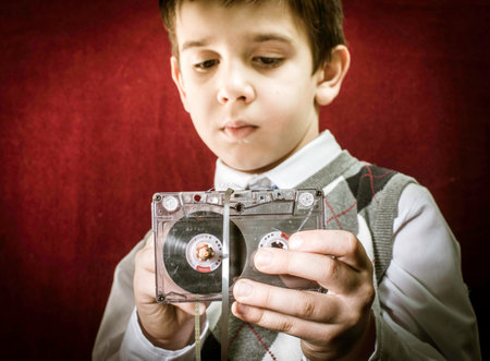 Rolled cassette strip with a pencil. Boy hold cassette tape. Close upの写真素材